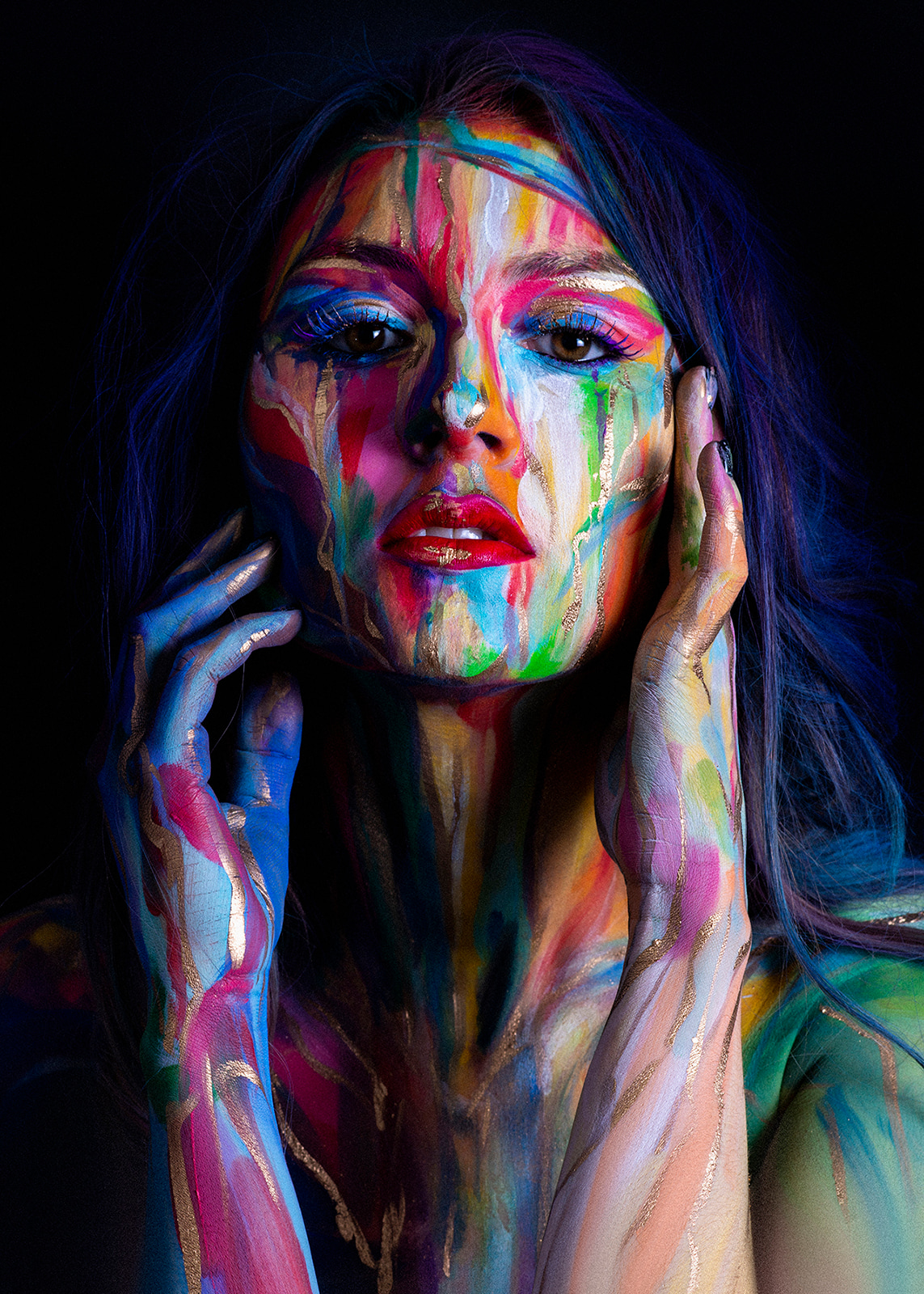 Close portrait of a woman with vibrant multicoloured artistic face paint.