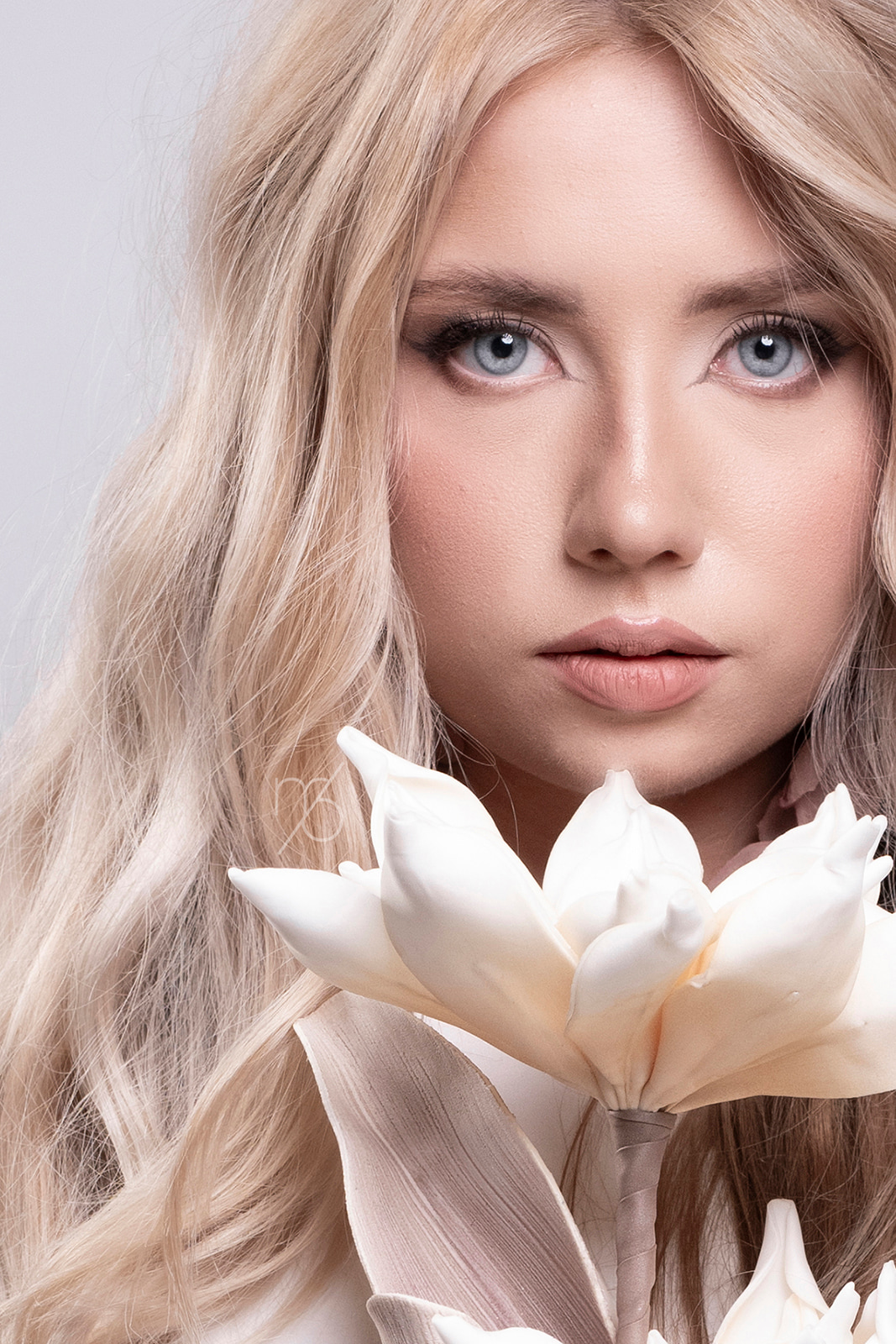 Blonde woman holding white flowers in a fine art beauty portrait.
