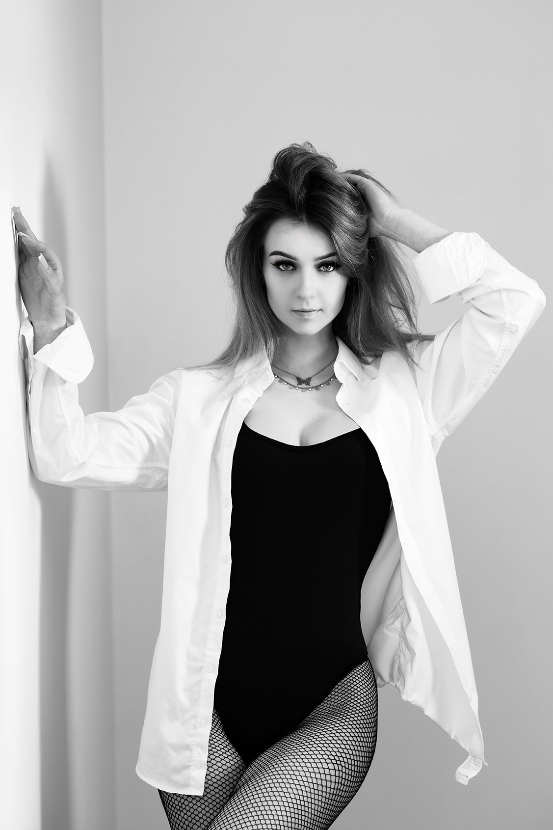 Black and white portrait of a woman standing beside a doorway.