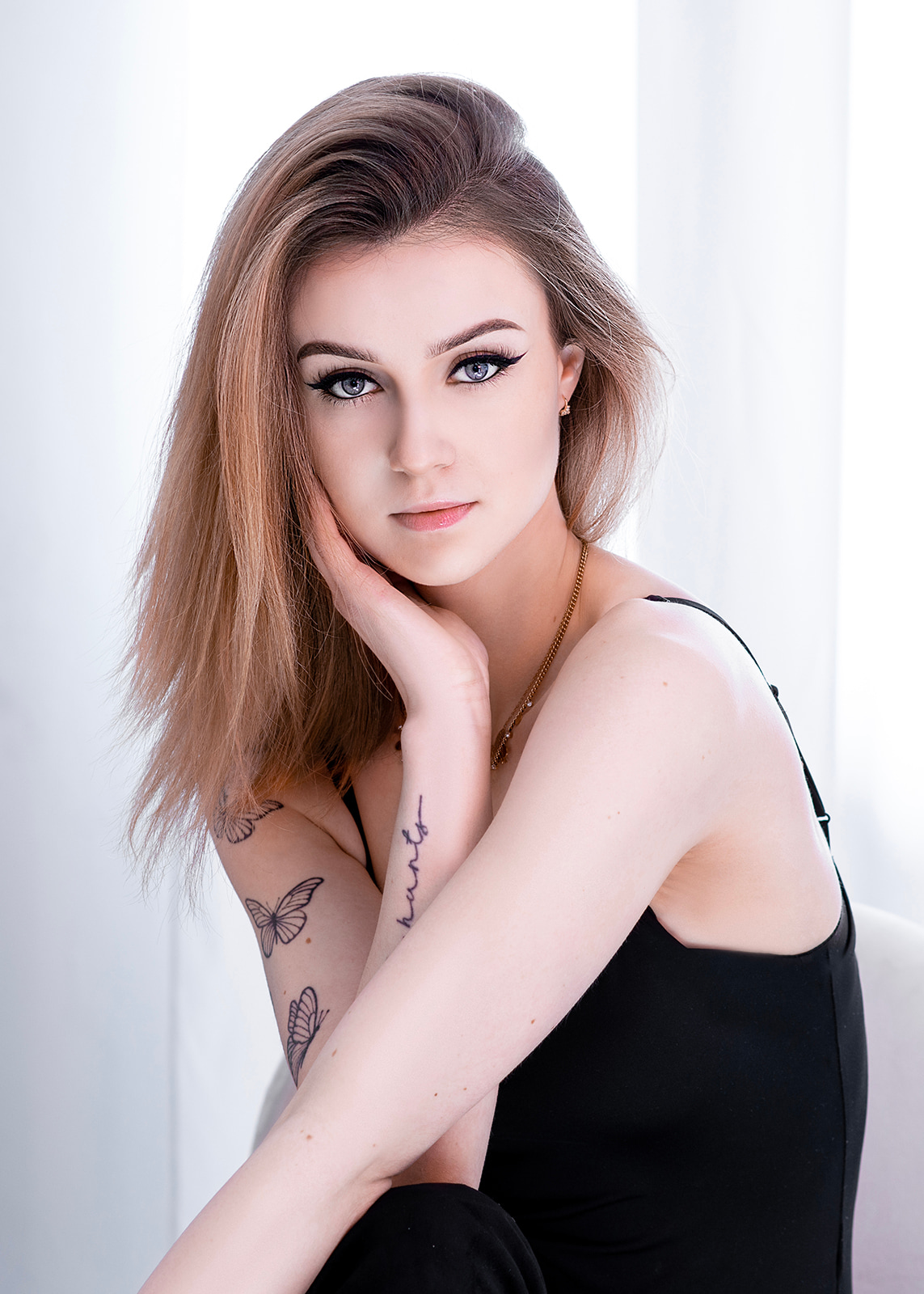 Close portrait of a young blonde woman against a bright neutral background.